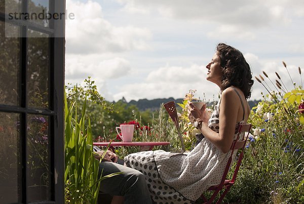 Frau auf dem Balkon trinkt Tee