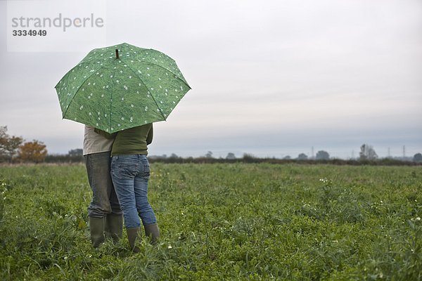 Paar unter Schirm im Feld