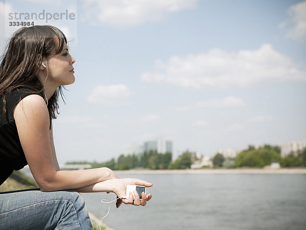 Frau hört Musik am Fluss