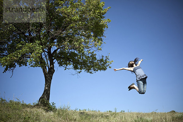 Frau beim Springen am Baum