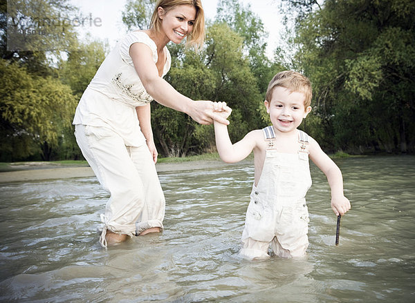 Mutter hält Kinderhand im Wasser