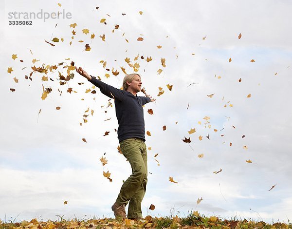 Mann  der durch fliegende Herbstblätter läuft