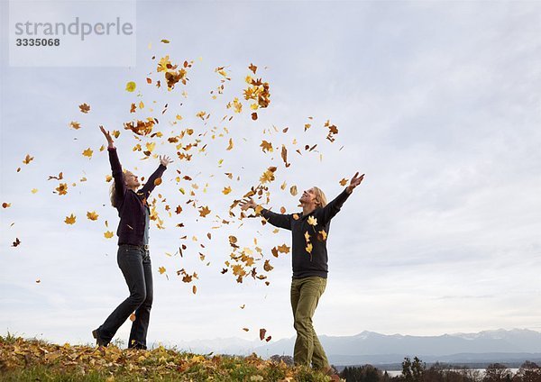 Frau und Mann beim Herbstlaubwerfen