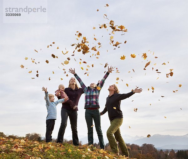 Familie wirft Herbstlaub in die Luft