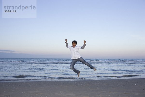 Ein Junge springt am Strand.