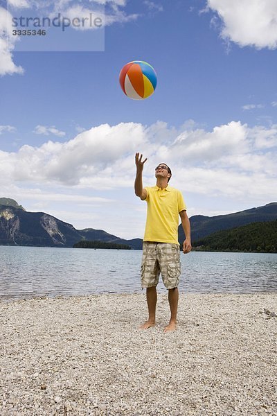 Ein junger Mann  der einen Strandball wirft.