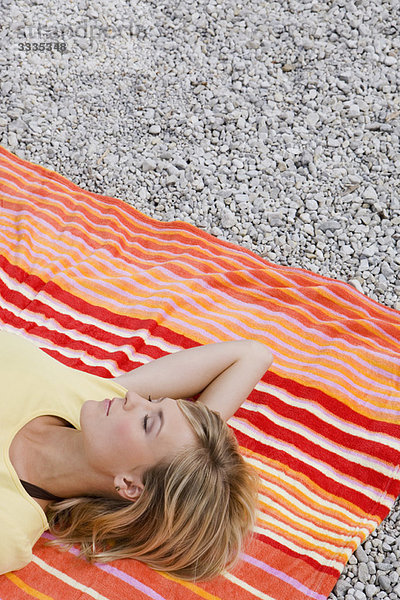 Ein Mädchen  das sich auf einem Strandtuch ausruht.