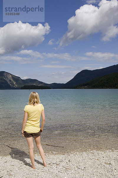 Eine junge Frau steht an einem See