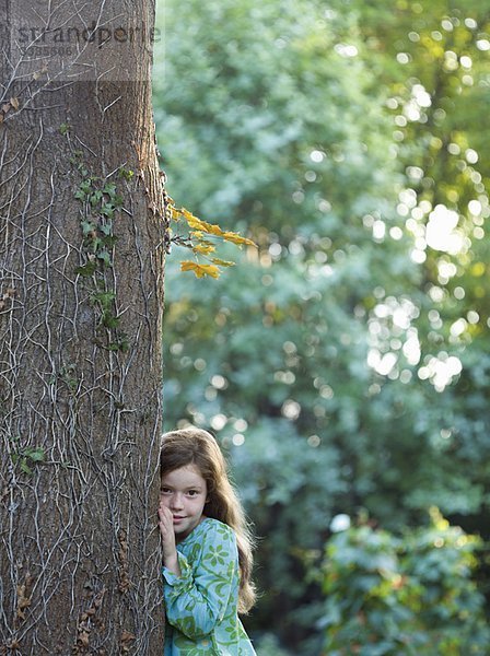 Junges Mädchen  das sich im Garten an einen Baum lehnt