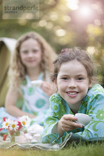 Zwei Mädchen lächeln beim Picknick.