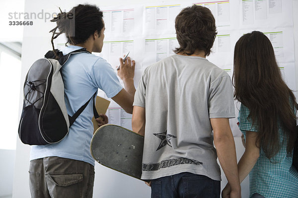 Studenten beim Überprüfen der Pinnwand  Rückansicht