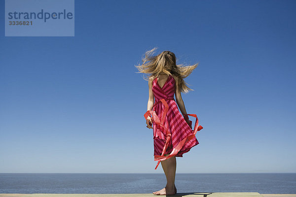 Junge Frau am Strand genießt Sonnenschein  Haare werfen