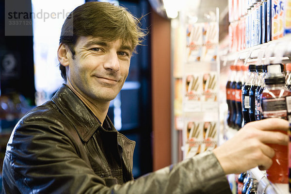 Mann am Softdrink-Kühler im Convenience Store