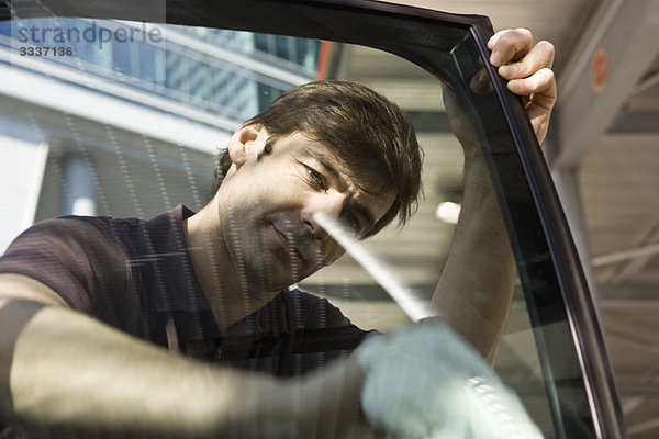 Mann reinigt Autotürfenster