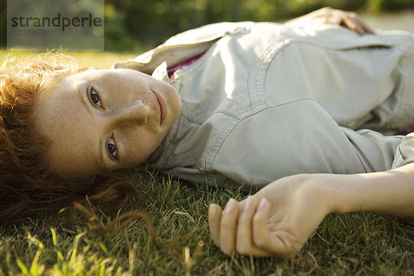 Junge Frau auf dem Rücken im Gras liegend