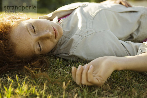 Frau auf dem Rücken im Gras liegend