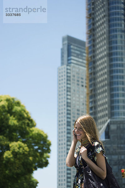 Junge Frau beim Telefonieren  Hochhäuser im Hintergrund