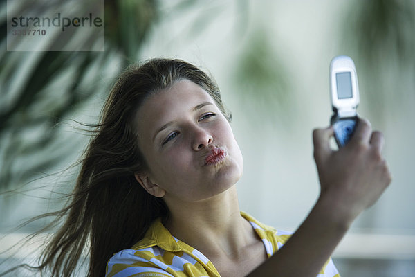 Junge Frau kräuselt die Lippen  fotografiert sich selbst mit dem Fotophon.