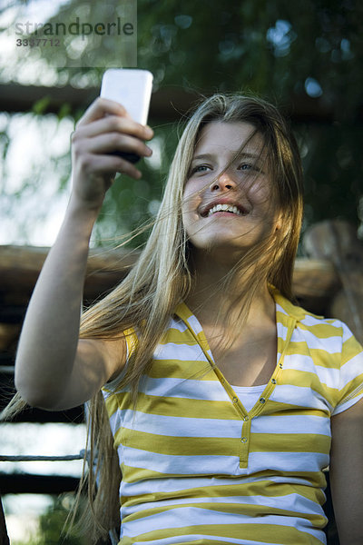 Junge Frau fotografiert sich selbst mit Digitalkamera
