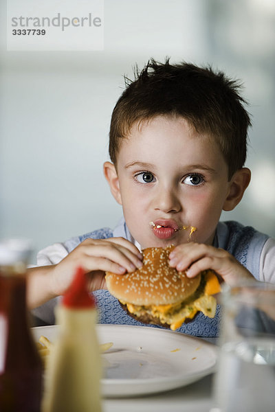 Kleiner Junge isst Cheeseburger