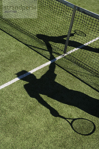 Schatten von Tennisspielern beim Händeschütteln über dem Spielfeldnetz