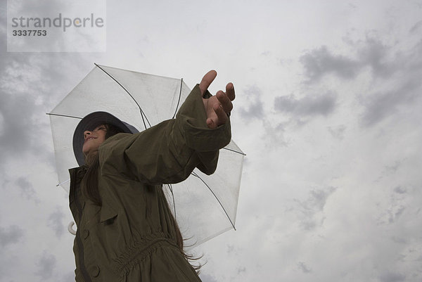 Frau mit Regenschirm  Arme ausgestreckt und Kopf zurück  wegschauend  lächelnd