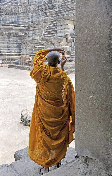 Buddhistischer Mönch schaut auf ein Handy  Angkor  Kambodscha  Rückansicht
