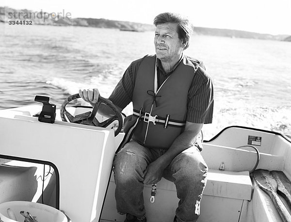 älterer Mann fahren ein Motorboot  Schweden.