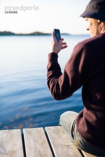 Mann auf einer Mole mit einem Mobiltelefon  Schweden.