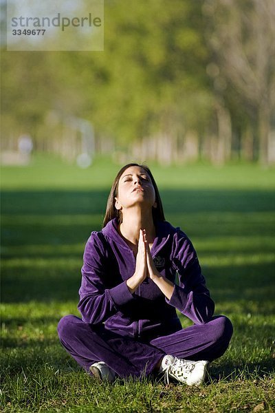 Junge Frau im Yoga Position  Arme  in einem Garten