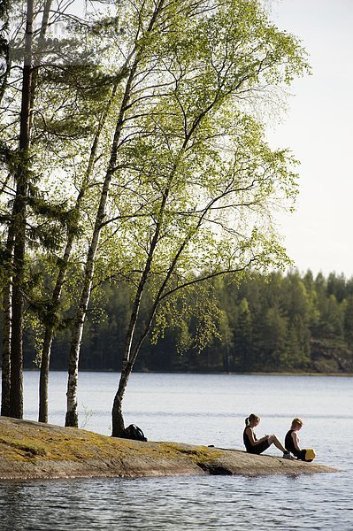 Zwei Leute sitzen an einem See  Schweden.