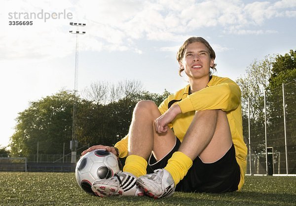 Kerl sitzend vom Fußballfeld