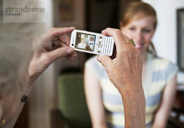 Ältere Frau beim Fotografieren einer jungen Frau mit Fotohandy