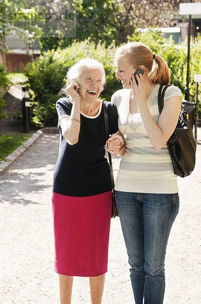 Zwei Frauen  die draußen auf dem Handy telefonieren.