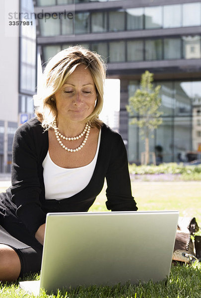 Geschäftsfrau im Park mit Laptop