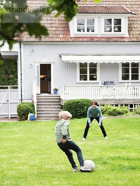 Mutter und Sohn spielen Fußball im Garten