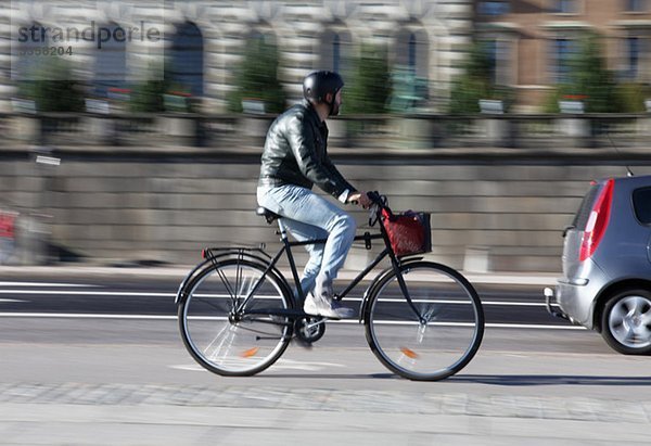 Mann mit dem Fahrrad die Straße hinunter