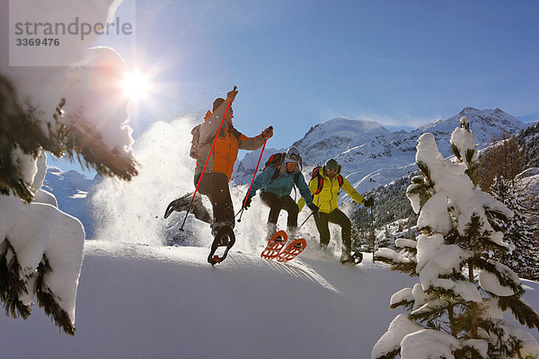 Schneeschuh Winter gelb Mensch rennen springen blau rot 3 Kanton Graubünden Engadin Oberengadin Schnee Schneeschuhlaufen Sonne Schweiz Wintersport
