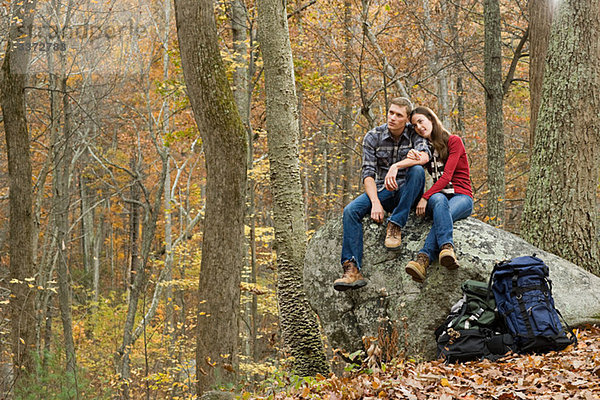 Junges Paar auf Felsbrocken im Wald sitzend