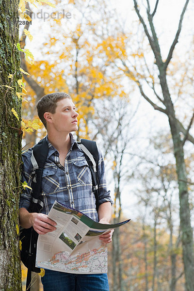 Junger Mann im Wald mit Karte