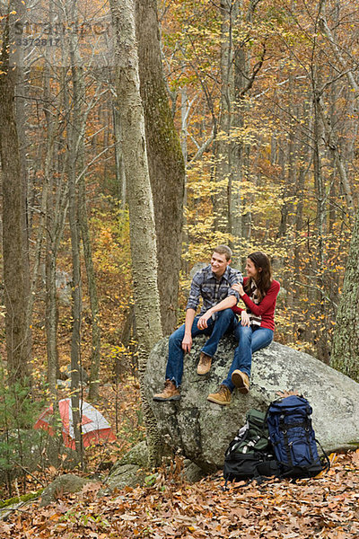 Junges Paar auf Felsbrocken im Wald sitzend