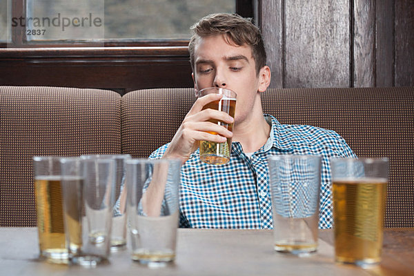 Junger Mann trinkt Bier in der Bar