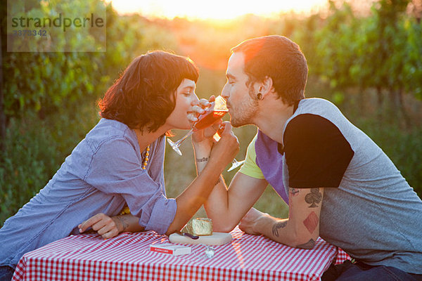 Pärchen  das auf einem Feld Wein trinkt.