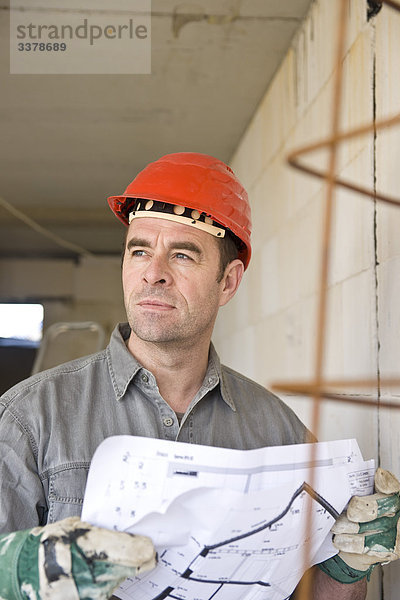 Mann mit Bauplan auf einer Baustelle  Flachwinkelansicht