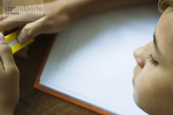 Mädchen mit Radiergummi  offenes Notizbuch auf dem Schreibtisch vor ihr