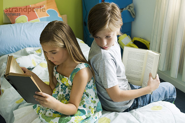 Geschwister lesen zusammen  Junge blickt über die Schulter zum Buch der Schwester