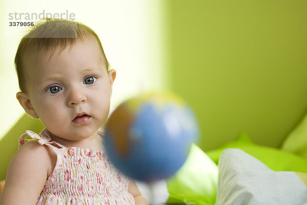 Kleinkind Mädchen betrachtet Spielzeug Globus