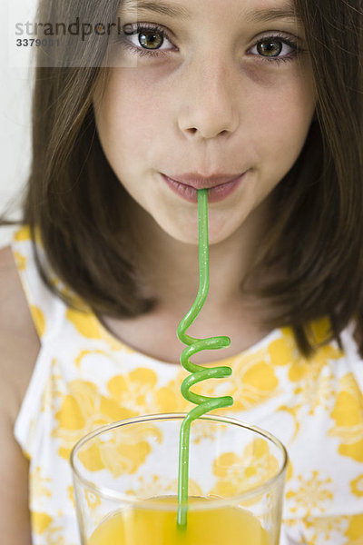 Mädchen trinken Saft durch gelockten Strohhalm