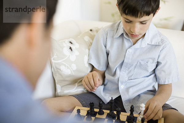 Junge  der mit seinem Vater Schach spielt  abgeschnitten