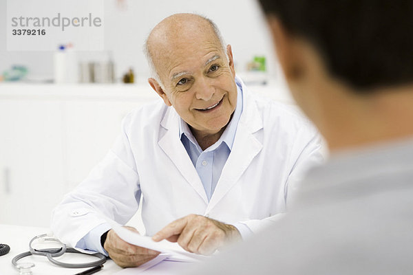 Arzt erklärt dem Patienten fröhlich positive Testergebnisse
